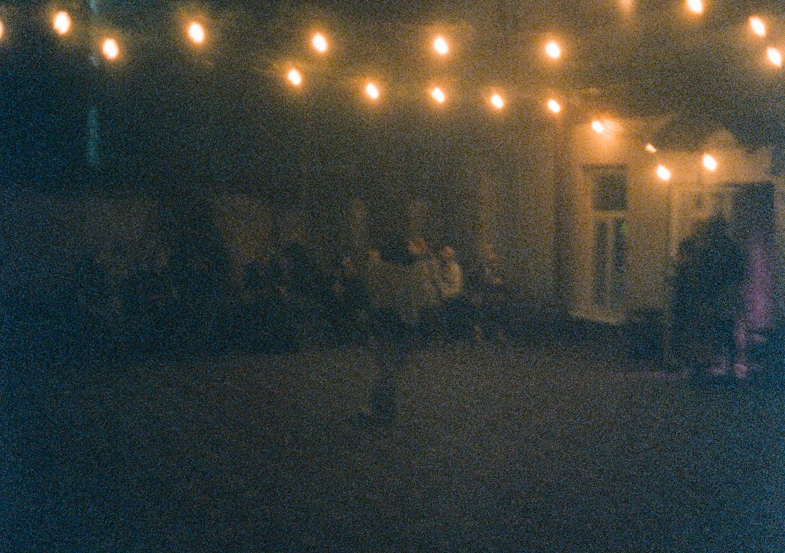 A summer-night outdoor gathering under string lights